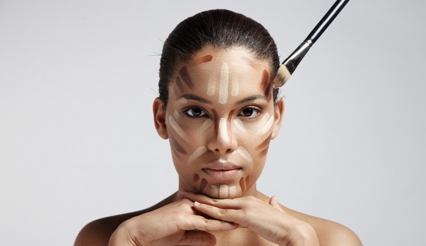 A woman is putting makeup on her face with a brush.