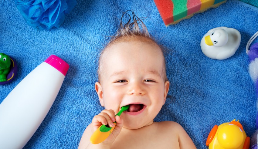 A baby is brushing his teeth with a toothbrush.