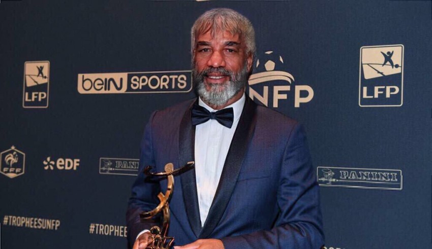 A man in a tuxedo holding an award.