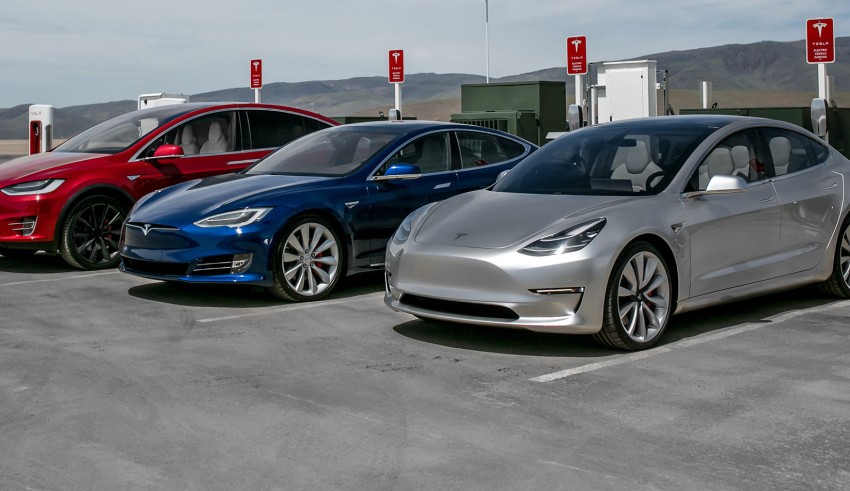 Three tesla model 3s parked in a parking lot.