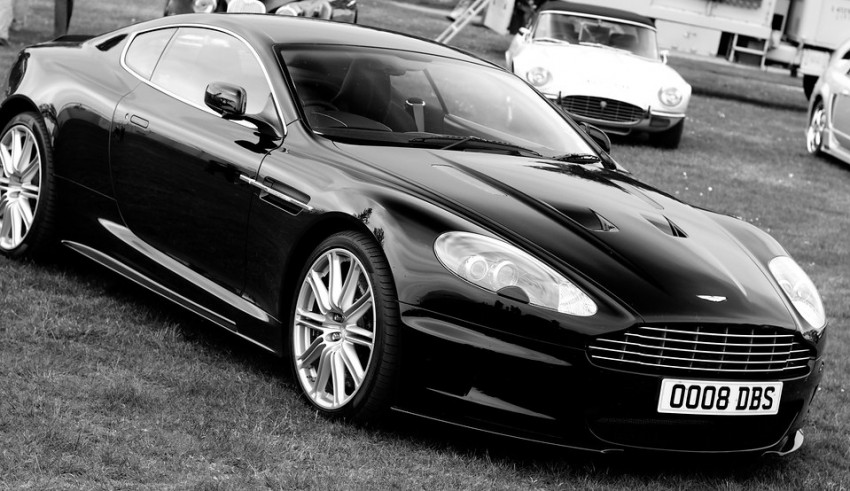 A black aston martin parked in the grass.