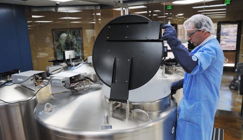 A man is working on a metal tank in a lab.