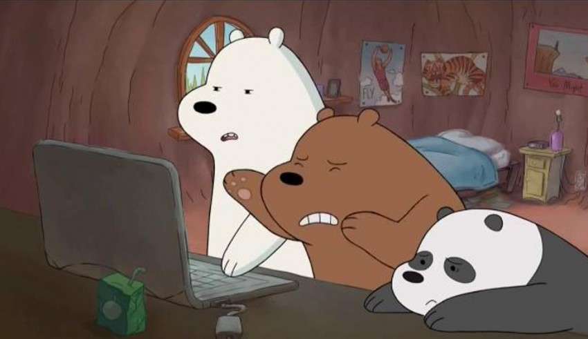 A bear and a panda sitting in front of a laptop.