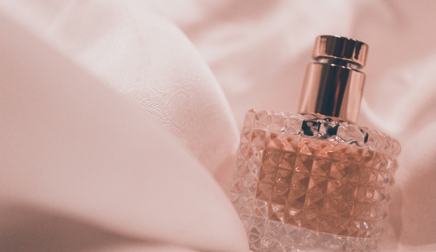 A bottle of perfume sitting on a bed.