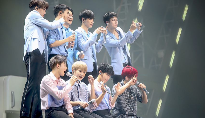 A group of korean boys sitting on a stage.