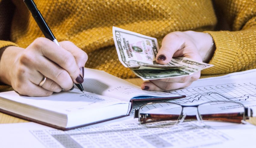 A woman's hand is holding a stack of bills and a calculator.