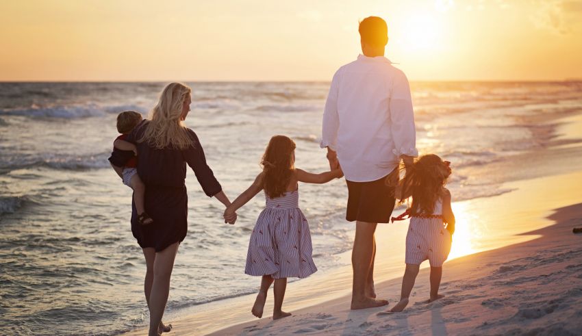 A family is walking on the beach at sunset.