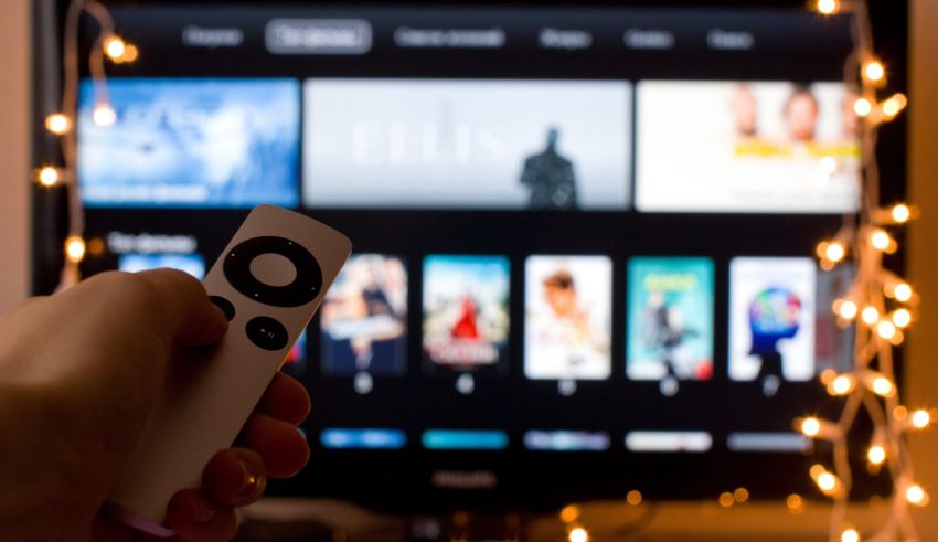 A person holding a remote control in front of a tv.