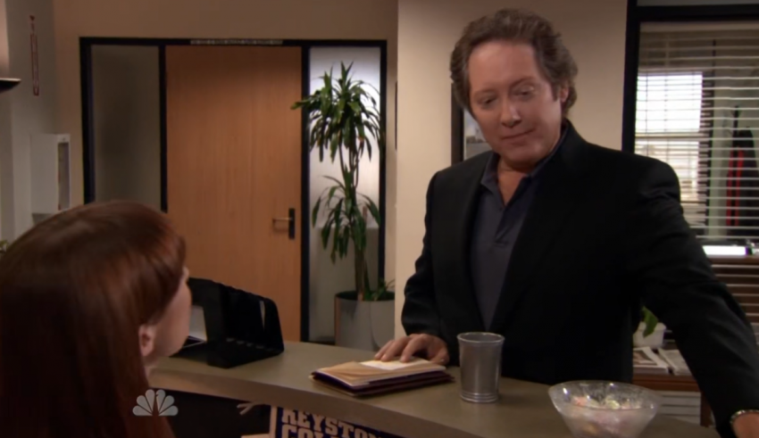 A man is talking to a woman at a desk.