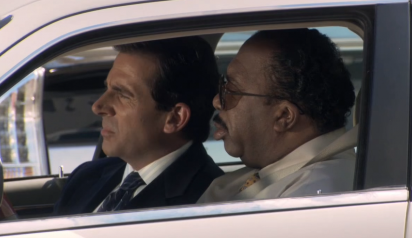 Two men sitting in the driver's seat of a white car.