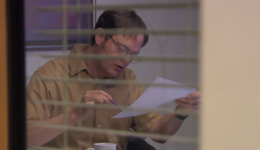 A man reading a piece of paper through a window.