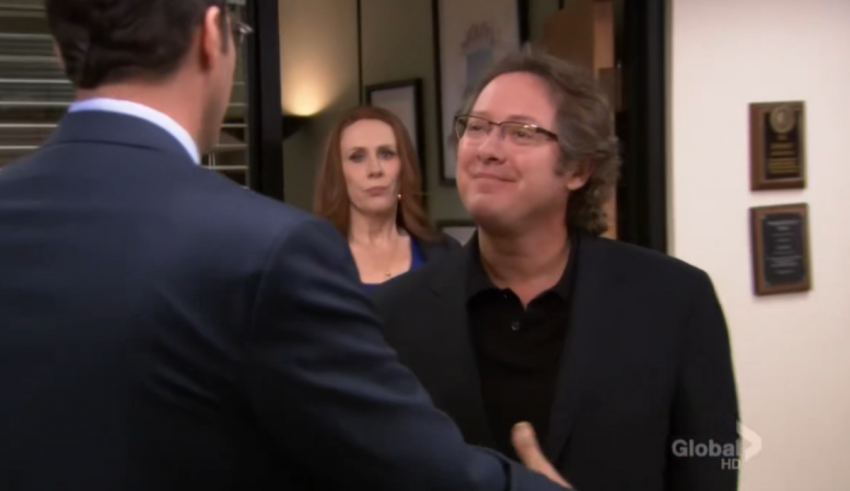 A man is shaking hands with another man in an office.