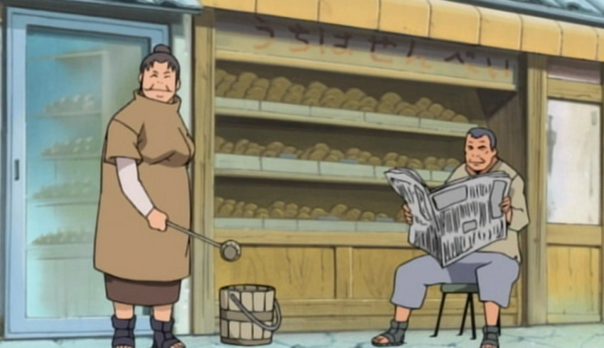 A man and a woman sitting on a bench in front of a bakery.