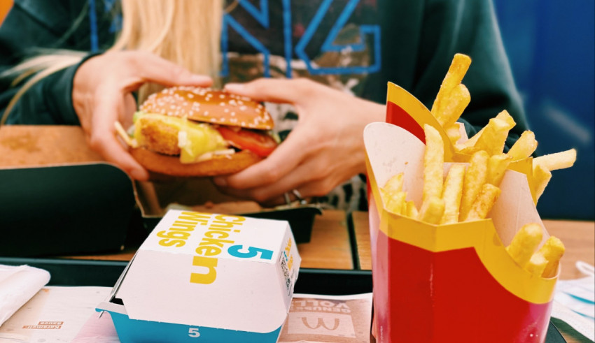 A woman is eating a burger and fries at a mcdonald's.