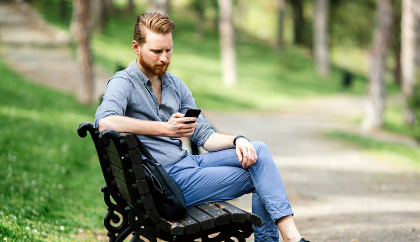 A man sitting on a park bench looking at his phone.