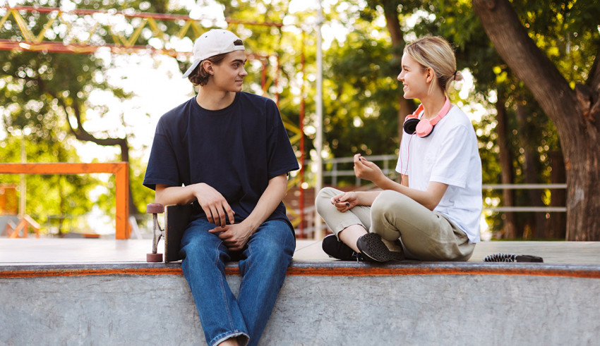Two people sitting on the edge of a skateboard ramp.