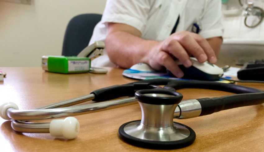 A stethoscope on a desk with a computer mouse.