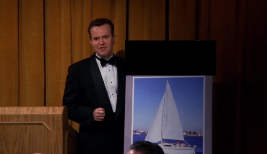 A man in a tuxedo standing in front of a picture of a sailboat.