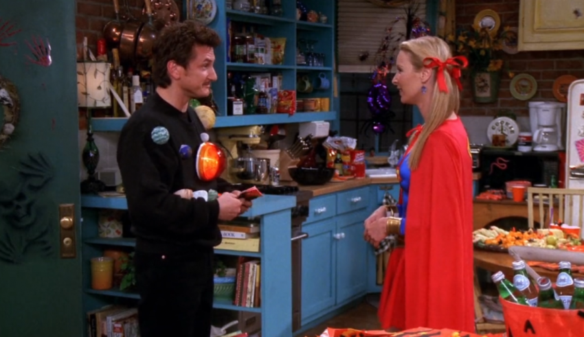 A man and woman dressed as superheroes in a kitchen.