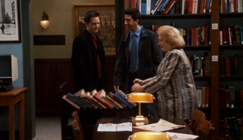 Three people standing around a table in a library.