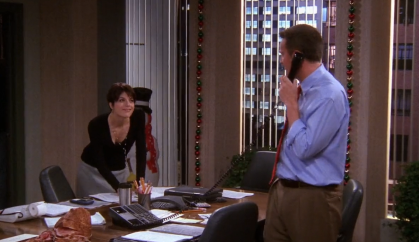 A man and woman talking on the phone in an office.
