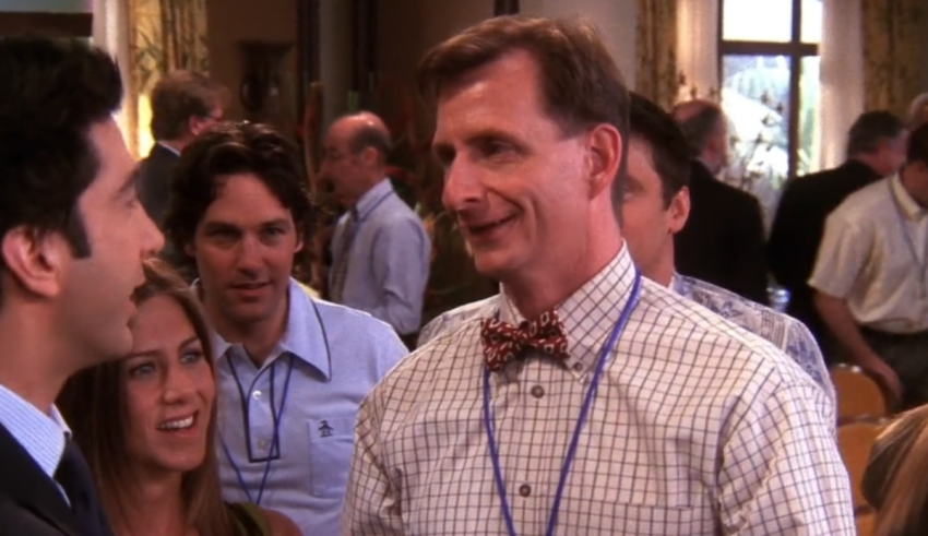A man in a bow tie talking to a group of people.