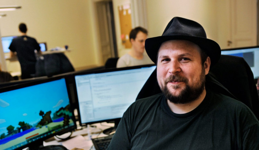 A man in a hat sitting in front of two monitors.