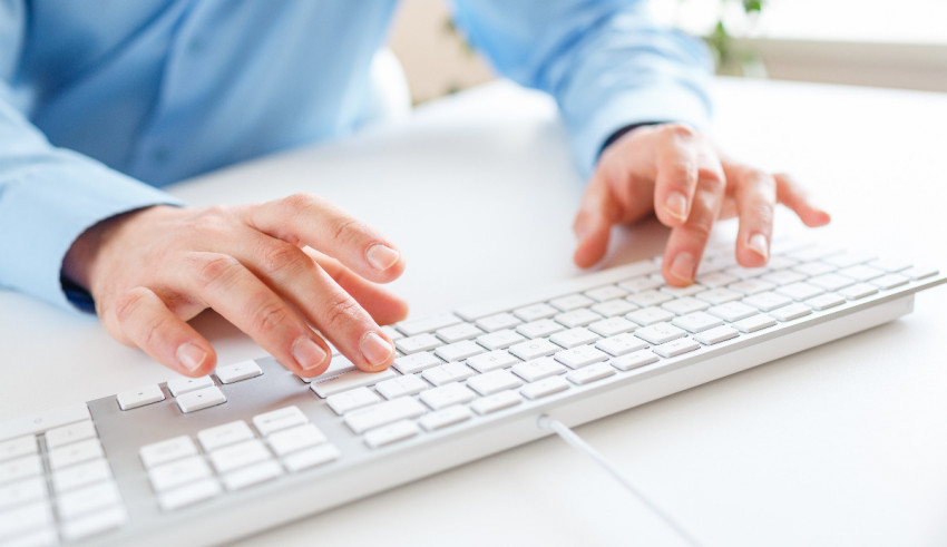 A man is typing on a computer keyboard.