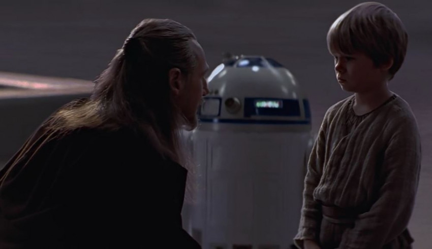 A young boy is standing next to a r2d2.