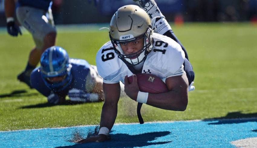 A football player diving for the ball on a field.