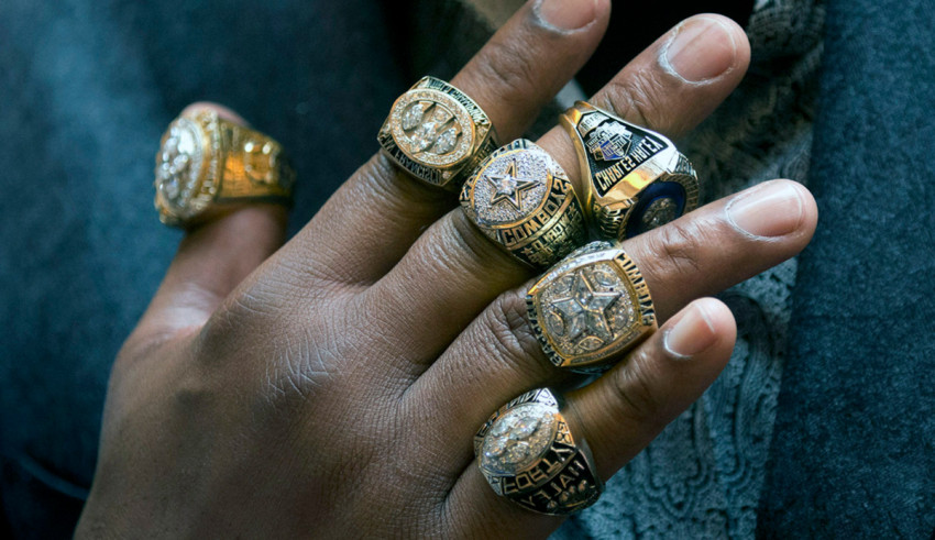 A man's hand with several rings on it.