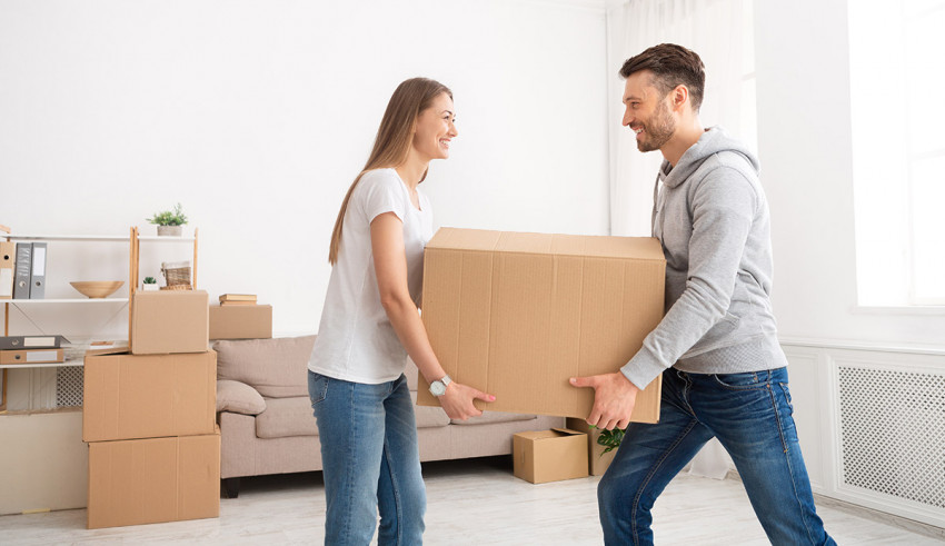 Young couple carrying moving boxes in the living room.
