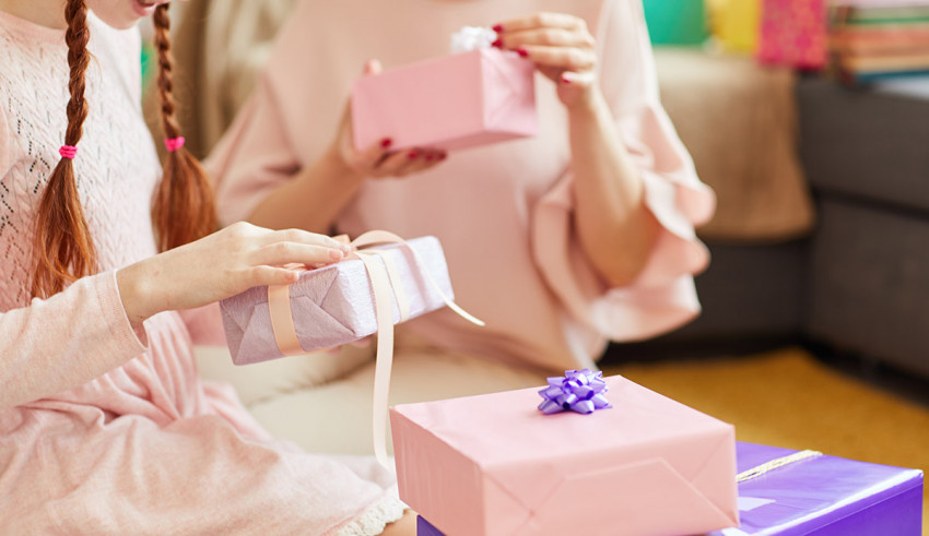 A mother and daughter are opening gifts in a living room.