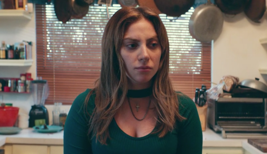 A woman in a green top standing in a kitchen.