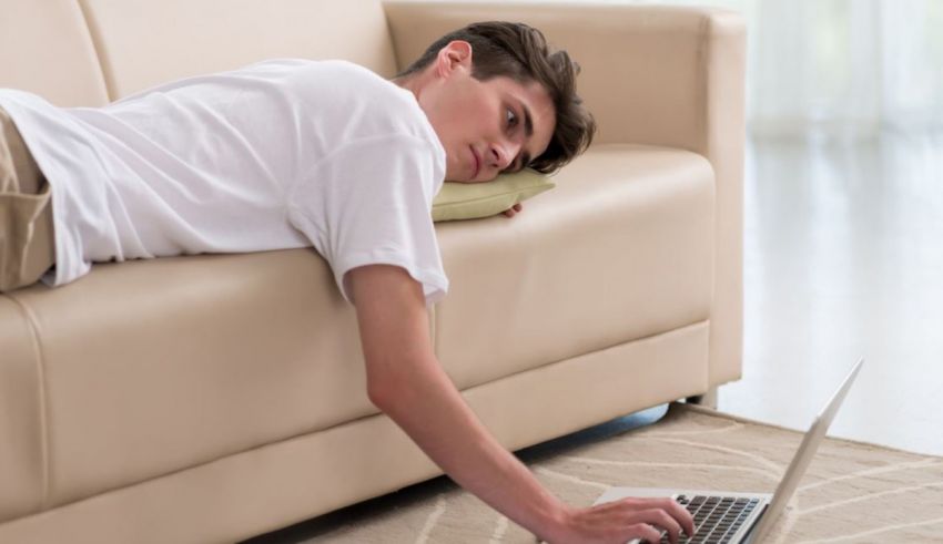 A man laying on a couch with a laptop on his lap.