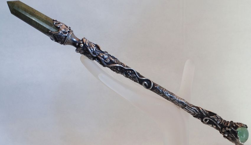 A silver wand with a green stone on it.