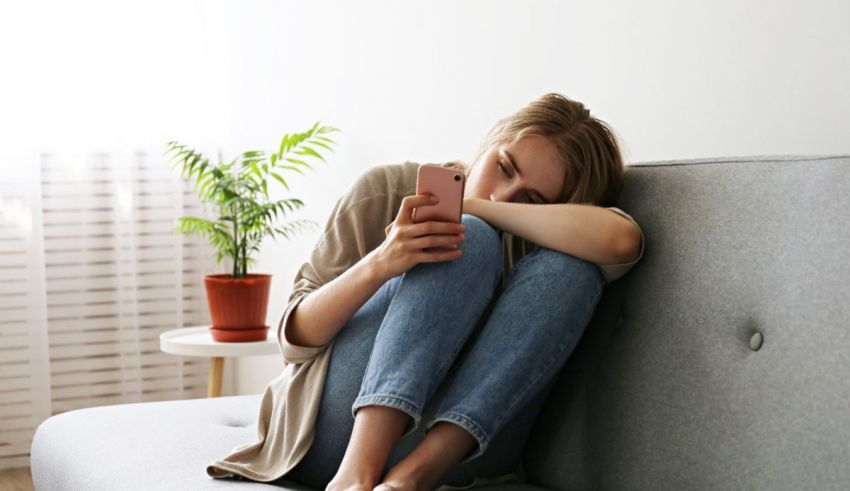 A woman is sitting on a couch with her phone in her hand.