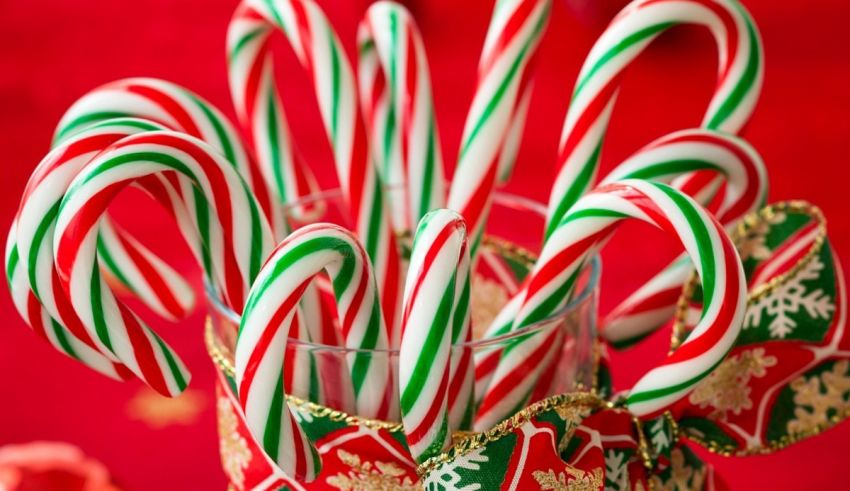 Candy canes in a glass vase on a red background.