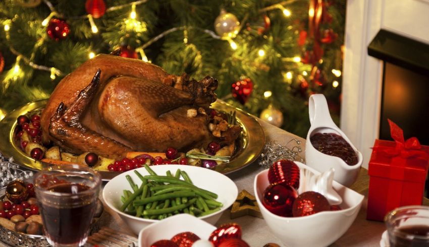 A turkey is sitting on a table in front of a christmas tree.