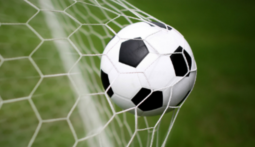 A soccer ball is in the net of a goal.