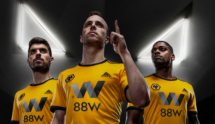 A group of men in yellow shirts posing in front of a dark background.