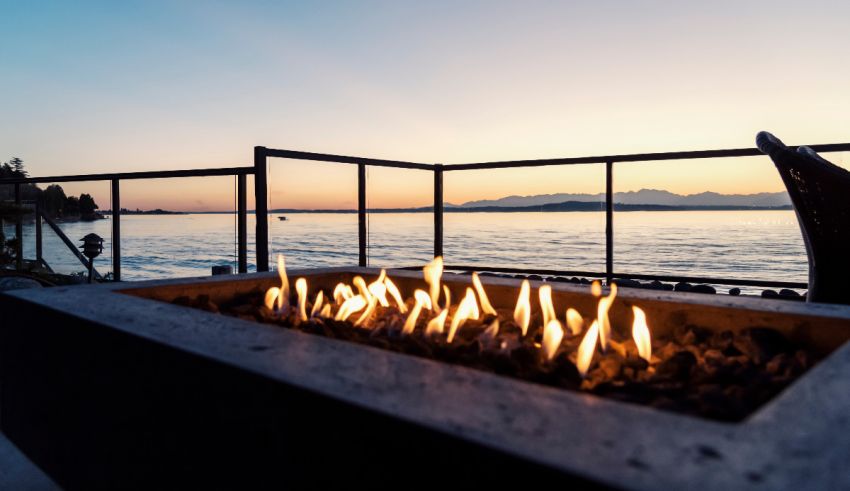 A fire pit on a deck overlooking the water.