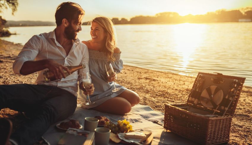 A couple enjoying a picnic on the beach at sunset.