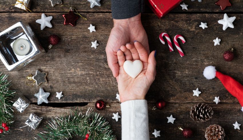 A couple holding a heart shaped cookie on a wooden table.