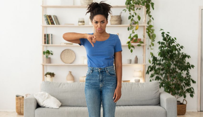 A young african american woman standing in front of a couch in her living room.