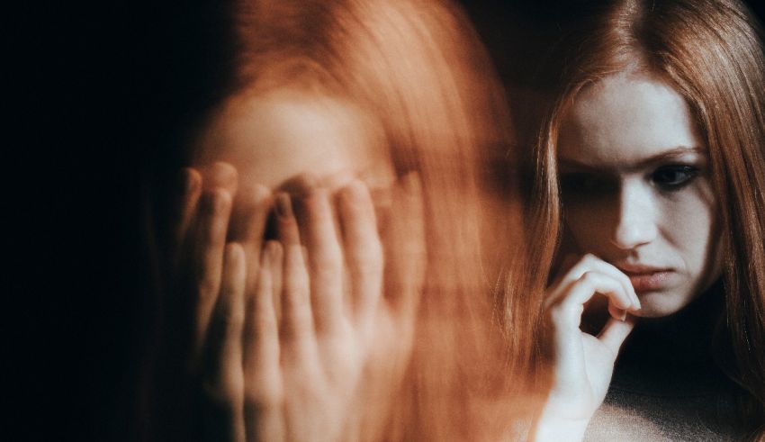 A woman with red hair is holding her hand in front of her face.