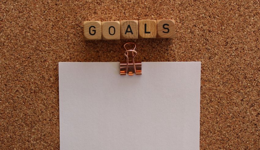 A piece of paper with the word goals attached to a cork board.
