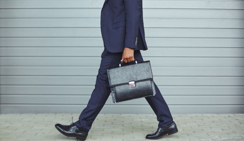 A black man in a suit walking with a briefcase.