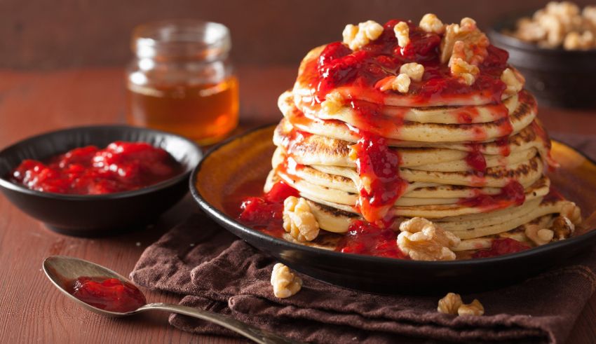 A stack of pancakes with syrup and walnuts.