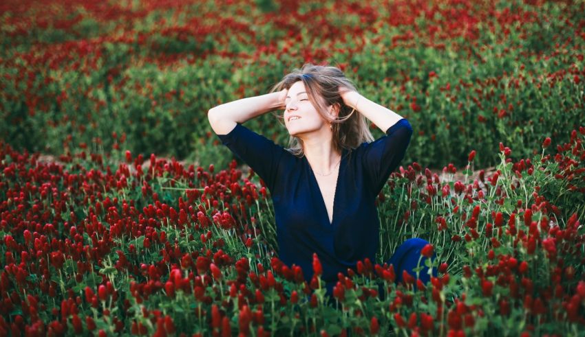 A woman is sitting in a field of red flowers.